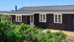 A row of dark wooden cabins with white-framed windows and a metal roof, surrounded by greenery. - Premium Holiday Home in FanÃ¸ near Beach (Fano)