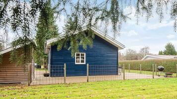 A blue single-story house with a fenced yard, a small porch, and a window.