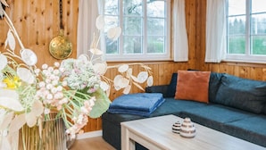 A cozy room with wooden walls, a sofa, a table, and a window with curtains. - 4 Person Holiday Home in Ansager (Ansager)