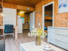 Un interior de madera con comedor, cocina y una cama.