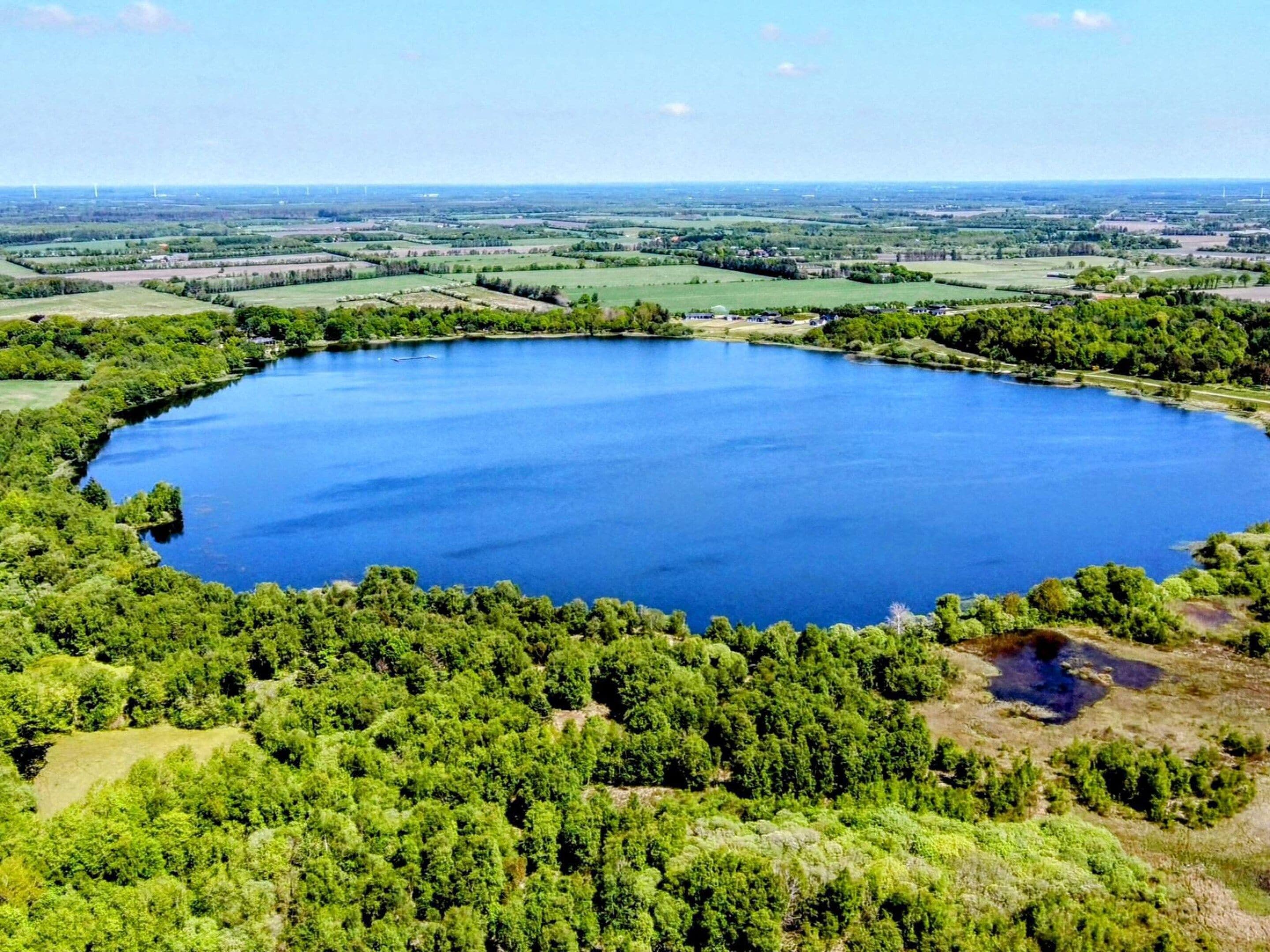 Un lago grande y circular rodeado de un bosque verde denso.
