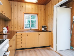 A wooden-paneled kitchen with a window, a coffee maker, and a white door. - 4 Person Holiday Home in Ansager (Ansager)