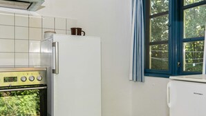 Cozinha com geladeira branca, fogão e janela com cortinas azuis.