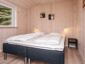 Una habitación con una cama, dos lámparas de pared y una mesita.