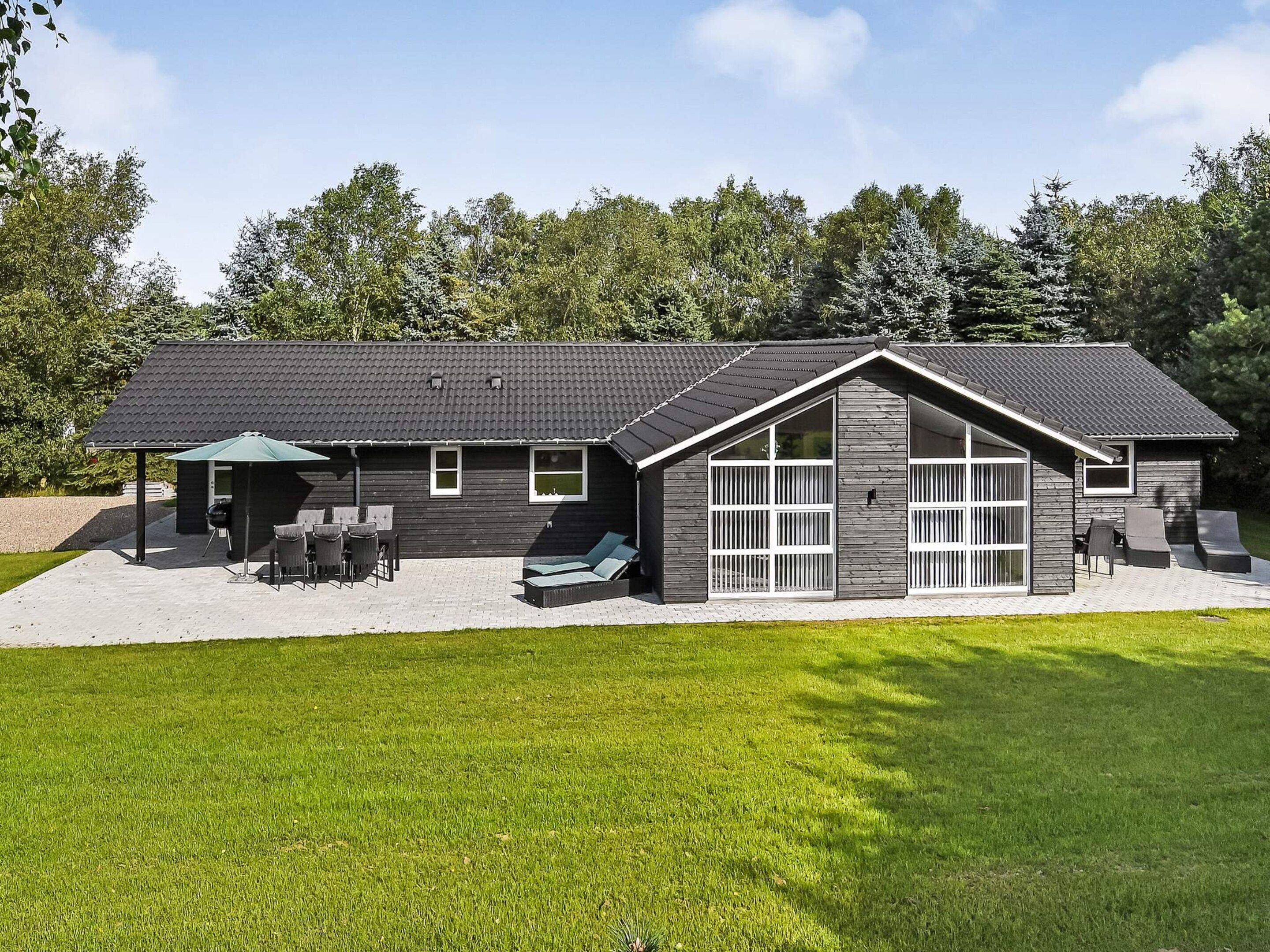 Una casa moderna con patio coperto, area salotto esterna e un ampio garage.