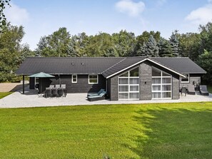 A modern house with a covered patio, outdoor seating, and a large garage. - 4 Star Holiday Home in Oksbol (Oksbol)