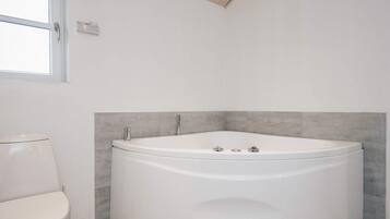 A modern bathroom with a freestanding bathtub, a toilet, and a window.