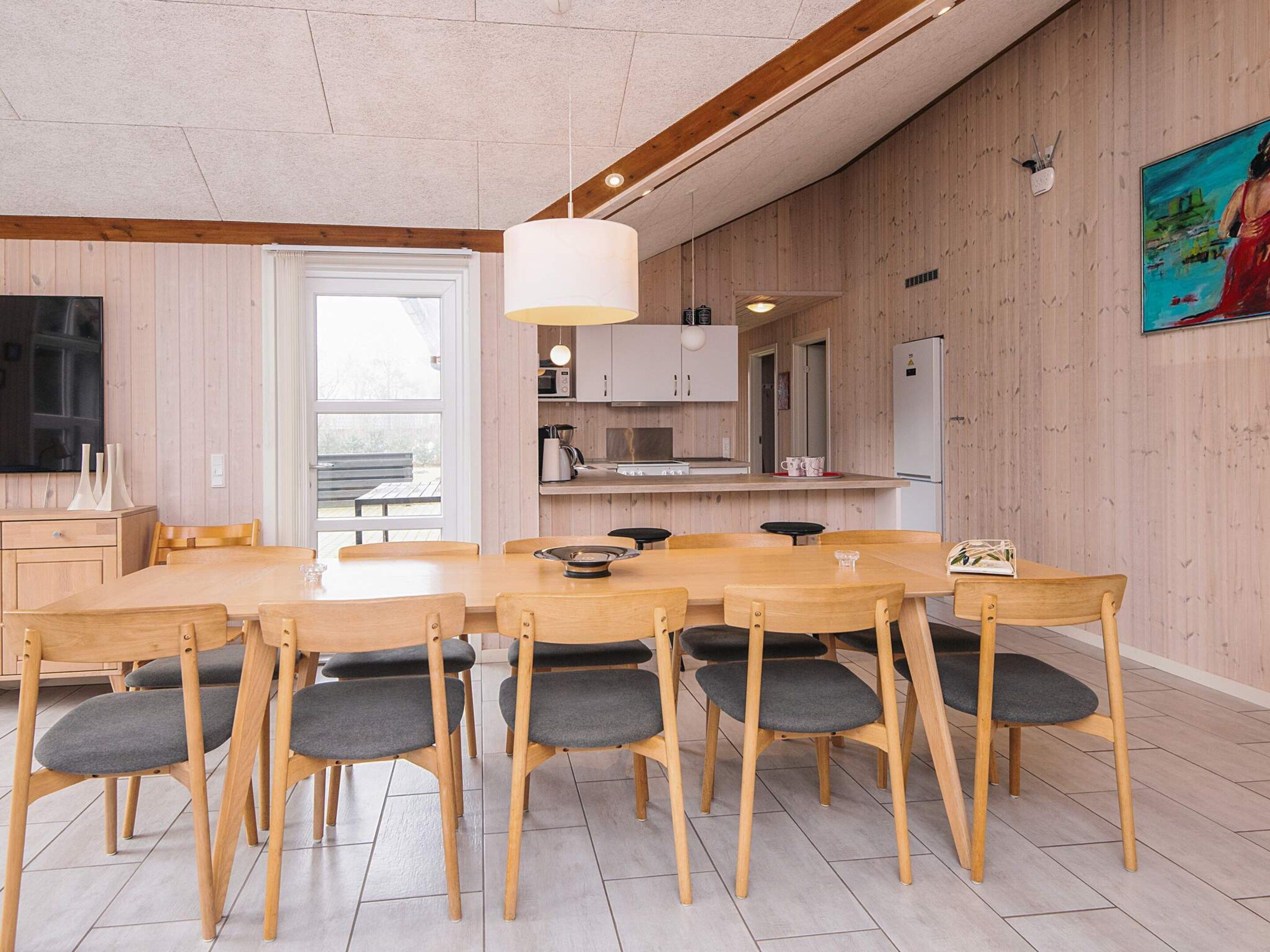 Una cocina moderna con armarios de madera, una isla central y una zona de comedor con una mesa grande y sillas.
