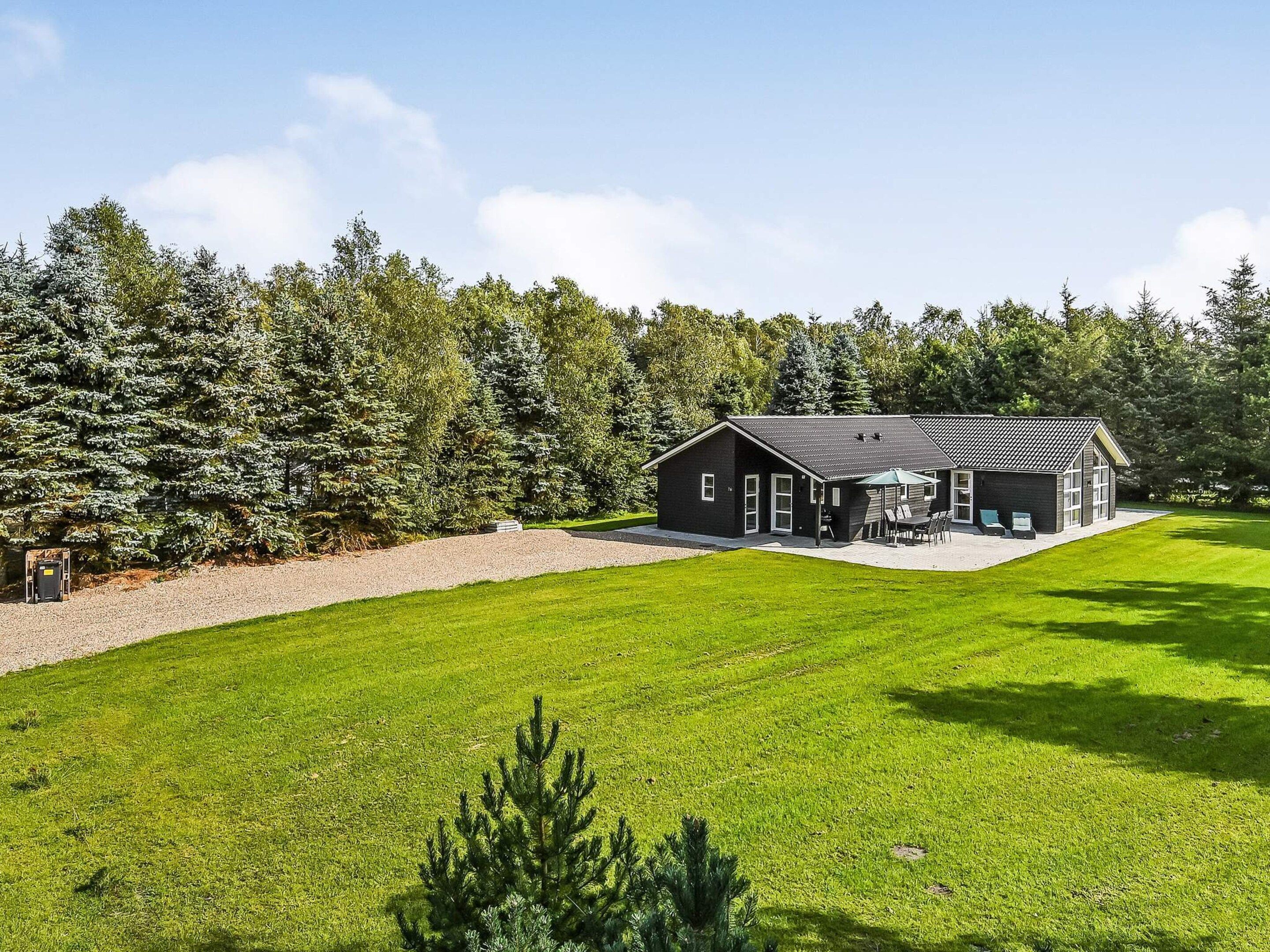 A modern house with a large lawn, a patio, and a garage.