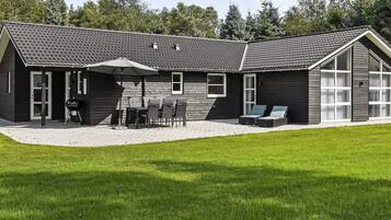 A modern house with a patio, outdoor furniture, and a barbecue grill.