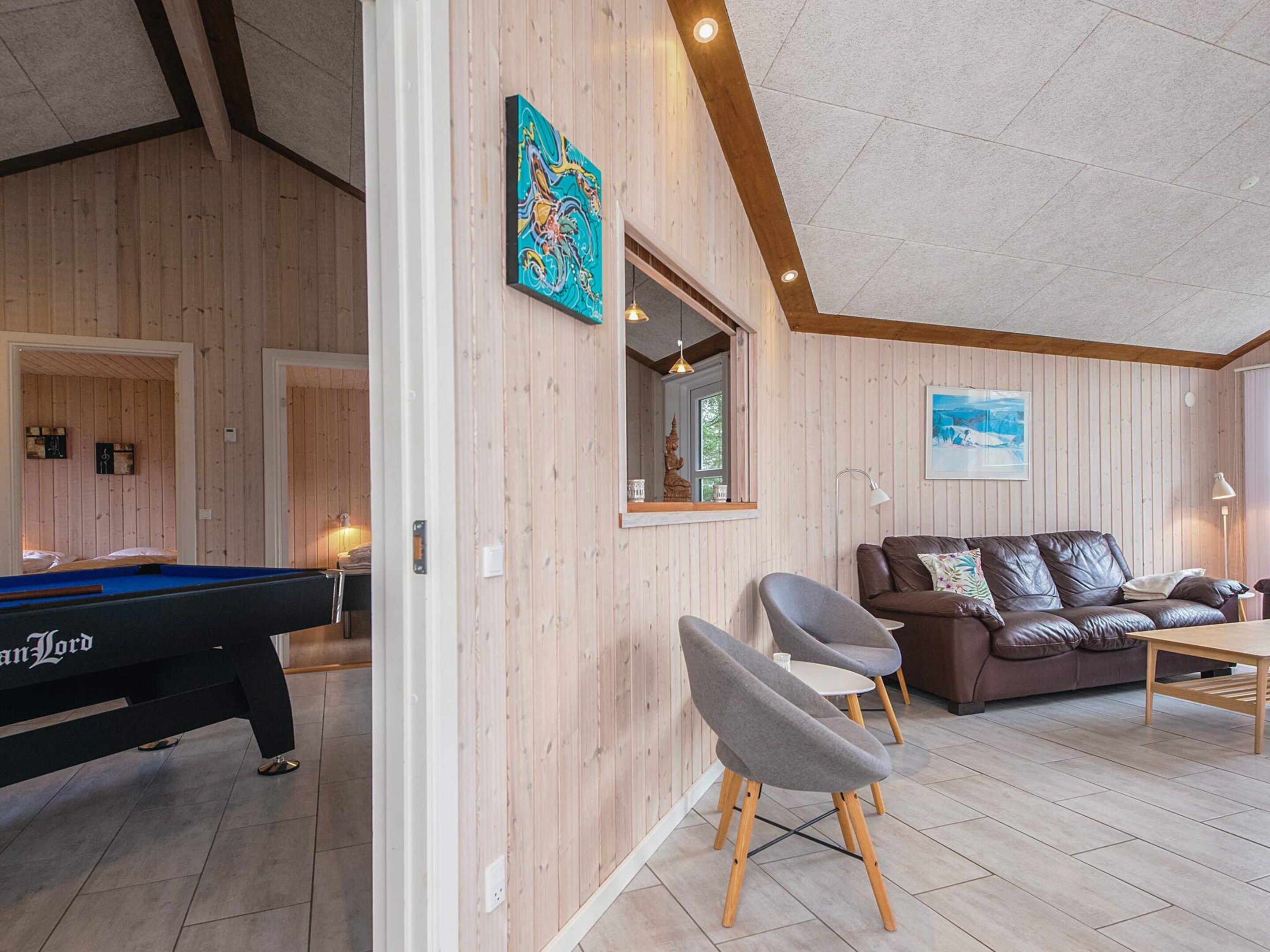 A room with a pool table, a sofa, and a dining table.