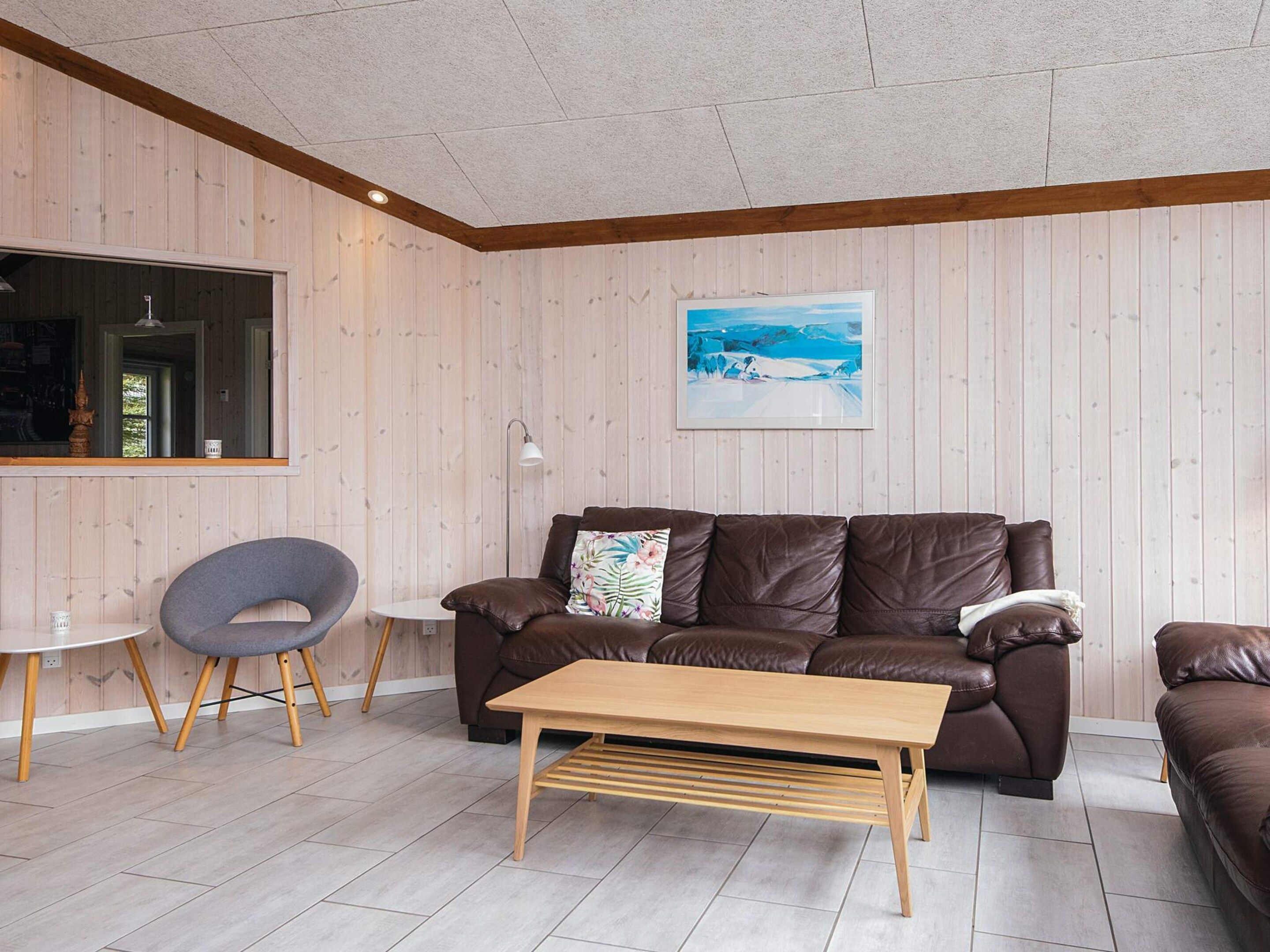 A modern living room with a brown leather sofa, a wooden coffee table, and a grey chair.