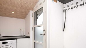 A laundry room with a washing machine, a drying rack, and a door with frosted glass panels. - Modernized Seaside Retreat-by Traum (Lokken)