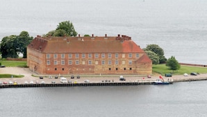 A large brick building with a flat roof, situated by a body of water.