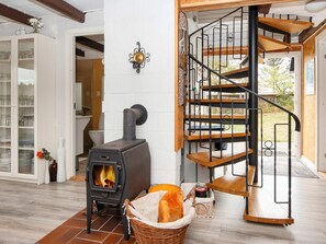 Una habitación con estufa de leña, una escalera de caracol y una pared de ladrillo blanco.