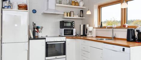A modern kitchen with white cabinetry, a built-in oven, a microwave, and a coffee maker.
