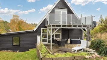 A modern house with a balcony, outdoor seating, and a garden area.