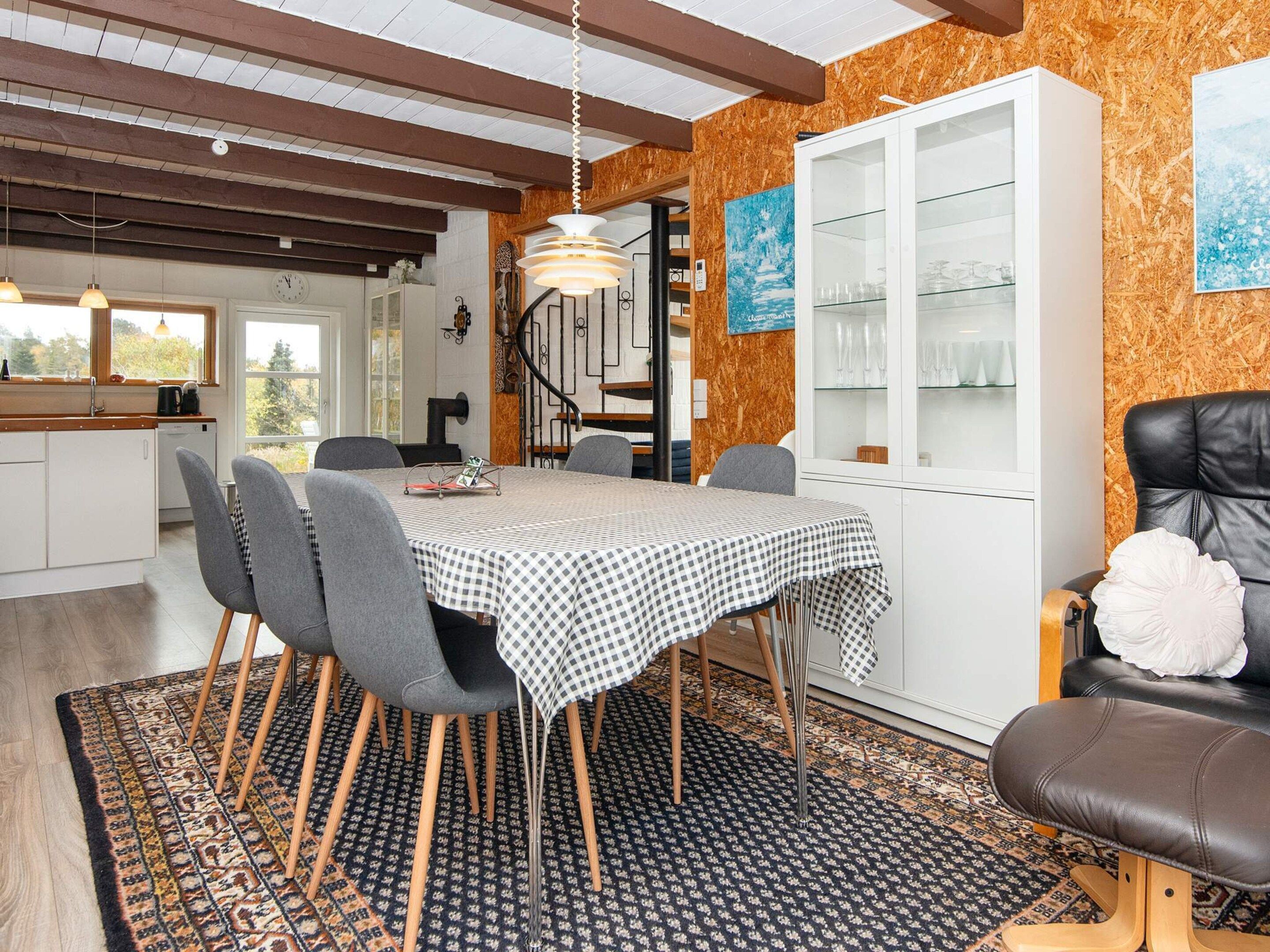 Un comedor con mantel a cuadros, sillas de madera y una alfombra estampada.