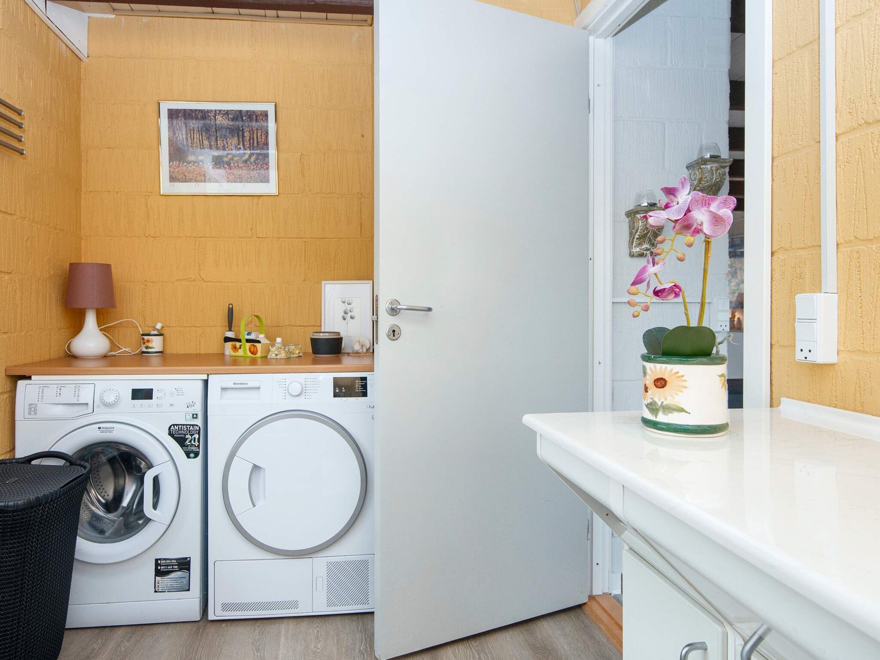 Un lavadero con lavadora, secadora y una puerta que da a otra habitación.