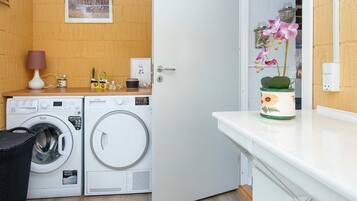 Un lavadero con lavadora, secadora y una puerta que da a otra habitación.