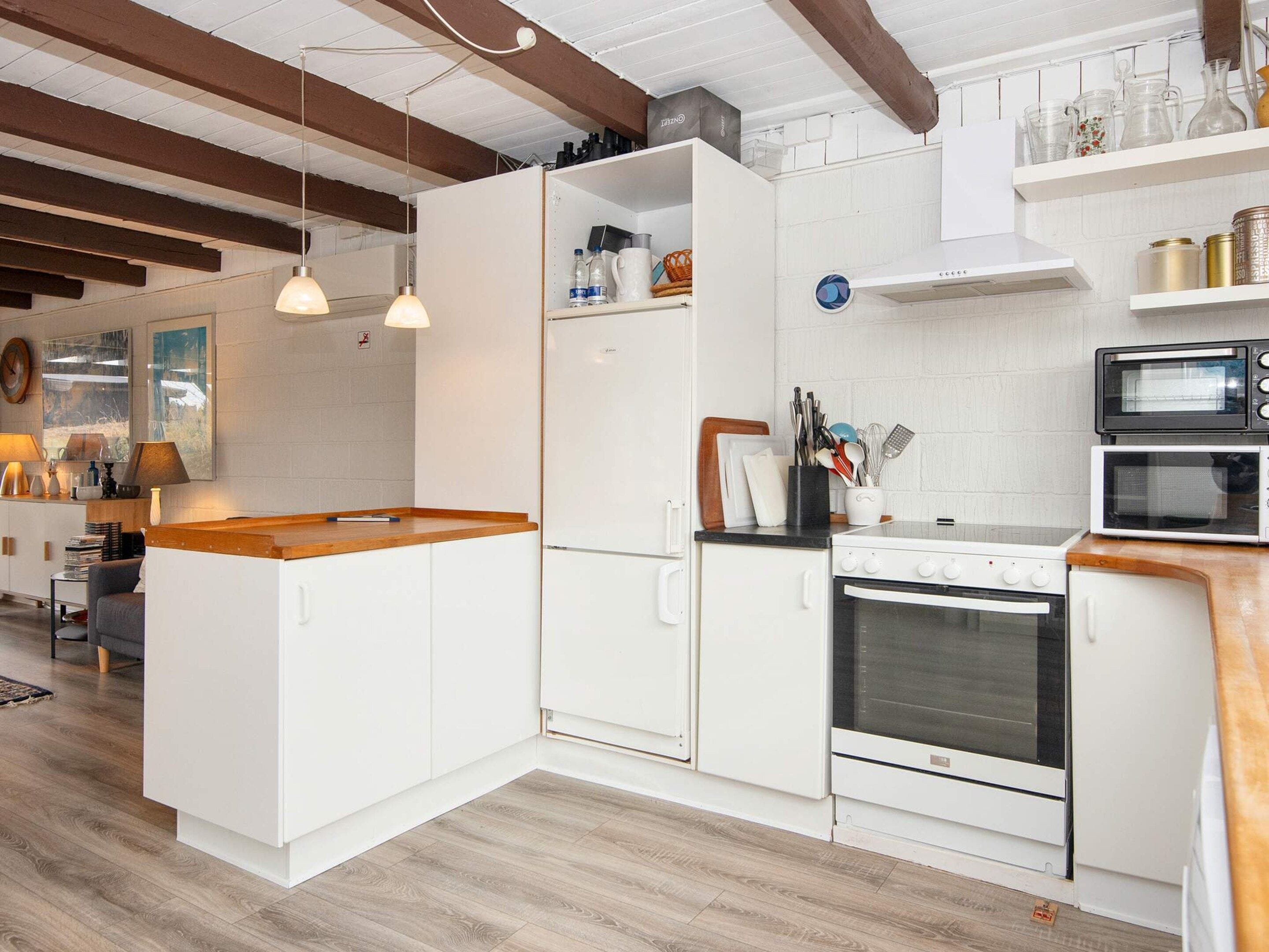 A modern kitchen with white cabinetry, a wooden countertop, and a built-in oven.