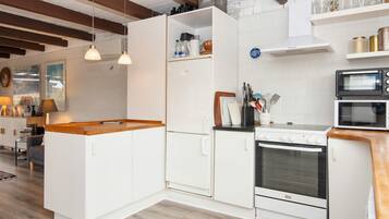 A modern kitchen with white cabinetry, a wooden countertop, and a built-in oven.
