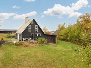 A two-story house with a dark exterior, a sloped roof, and a front porch with outdoor seating.