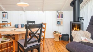 Ein gemütliches Zimmer mit Holzboden, einem runden Tisch mit Stühlen, einem Bücherregal, einem Kamin und einer komfortablen Sitzecke.