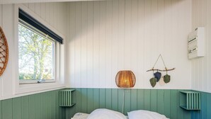 Ein Zimmer mit einem Bett, einem Fenster, einer Wandleuchte und einer Wand-Klimaanlage.