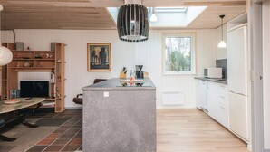 A modern kitchen with a central island, wooden ceiling, and a large window providing natural light. - 8 Person Holiday Home in Blavand (Blavand)
