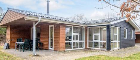 Una casa moderna con porche cubierto, ventanas amplias y chimenea.