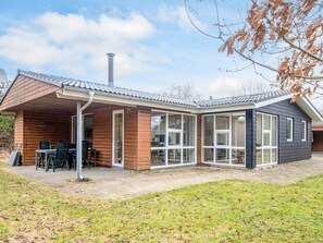 Une maison moderne dotée d’un patio couvert, de grandes fenêtres et d’une cheminée.