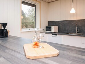 A modern kitchen with a microwave, sink, and wooden countertop. - 8 Person Holiday Home in Blavand (Blavand)