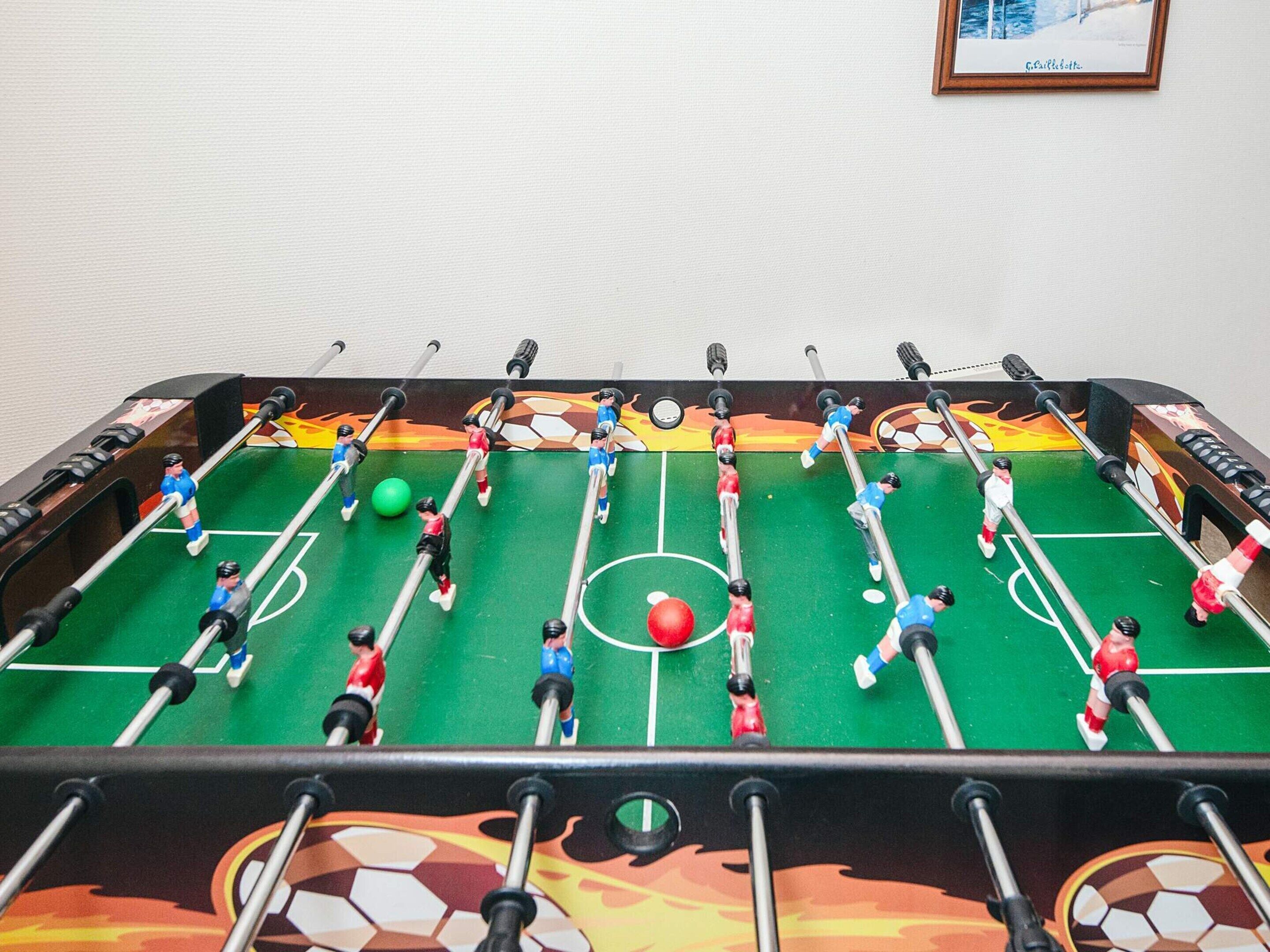 A foosball table with a soccer field design, including goalposts and a ball.