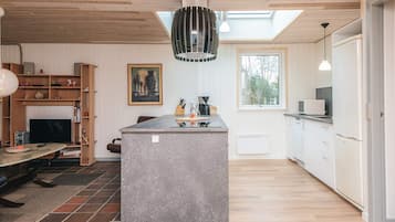 Une cuisine moderne avec un îlot central, un plafond en bois et une grande fenêtre.