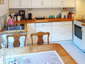 A kitchen with white cabinets, a wooden countertop, a sink, a coffee maker, and a stove. - 8 Person Holiday Home in Fløyrli (Sandnes)