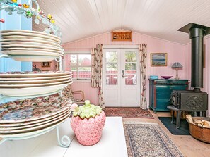 A cozy room with a white door, a blue cabinet, a pink strawberry-shaped vase, and a black stove. - Holiday Home in Snedsted near Sea (Thisted)