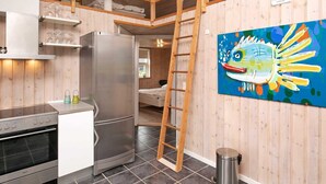A compact kitchen with a refrigerator, oven, and wooden cabinets. A ladder is leaning against the wall, and a trash can is visible. - 6 Person Holiday Home in Humble (Sydlangeland)