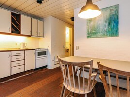 A compact kitchen with white cabinets, a stove, and a dining table with two chairs.