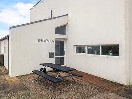 Un edificio con fachada blanca, una puerta y una ventana con plantas en macetas.