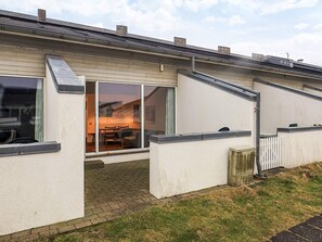Un immeuble résidentiel doté d’un patio, d’une porte-fenêtre coulissante et d’une clôture blanche en bois.
