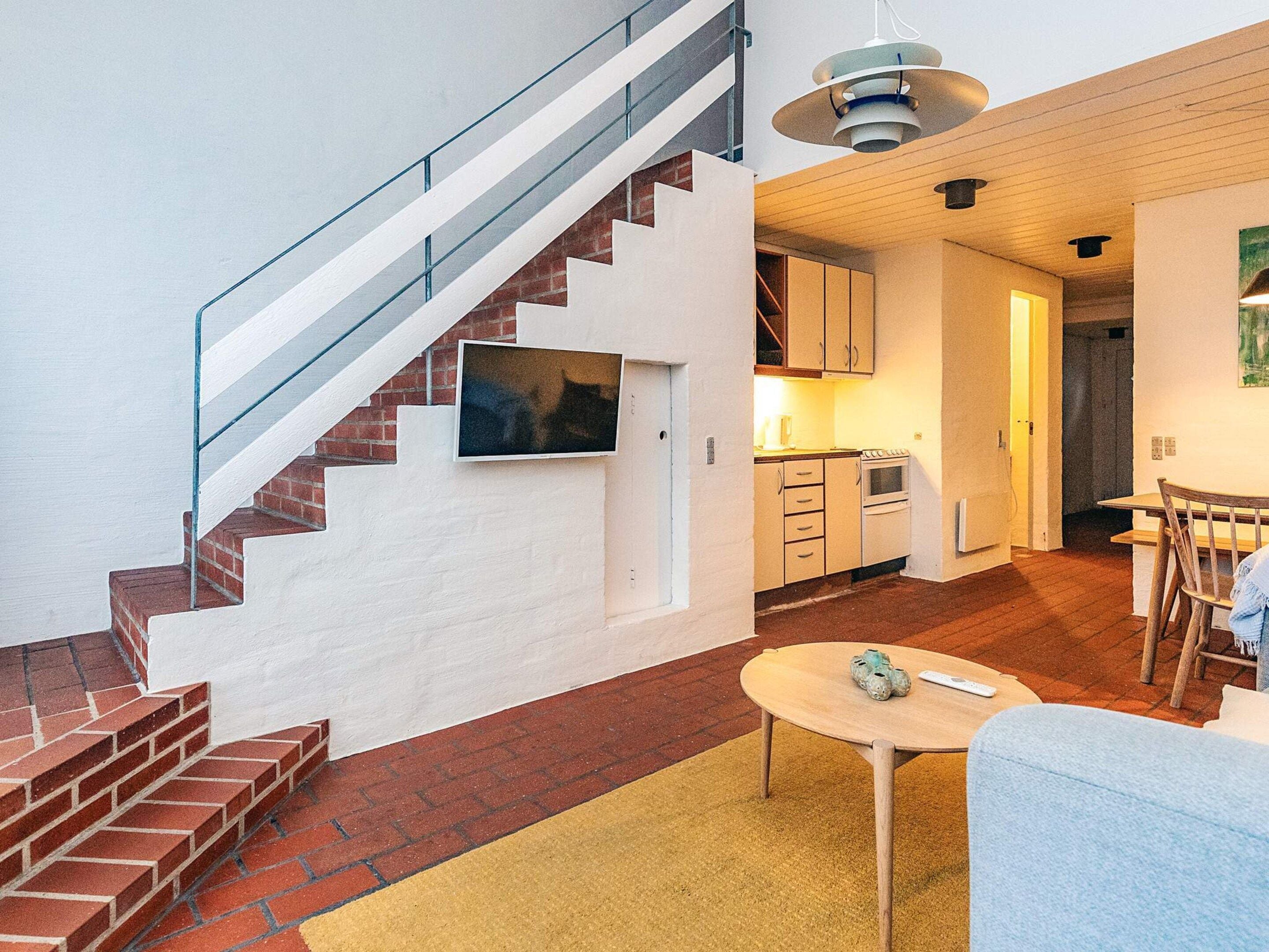 A modern apartment with a staircase, kitchen, dining area, and living room.