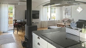 A modern kitchen with a central island, a stove, and a dining area with a table and chairs. - Holiday Home in Henån (Henån)