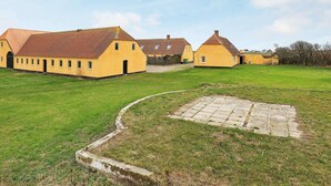 A yellow building with a large open lawn and a paved area in the foreground. - 12 Person Holiday Home in Lemvig (Lemvig)