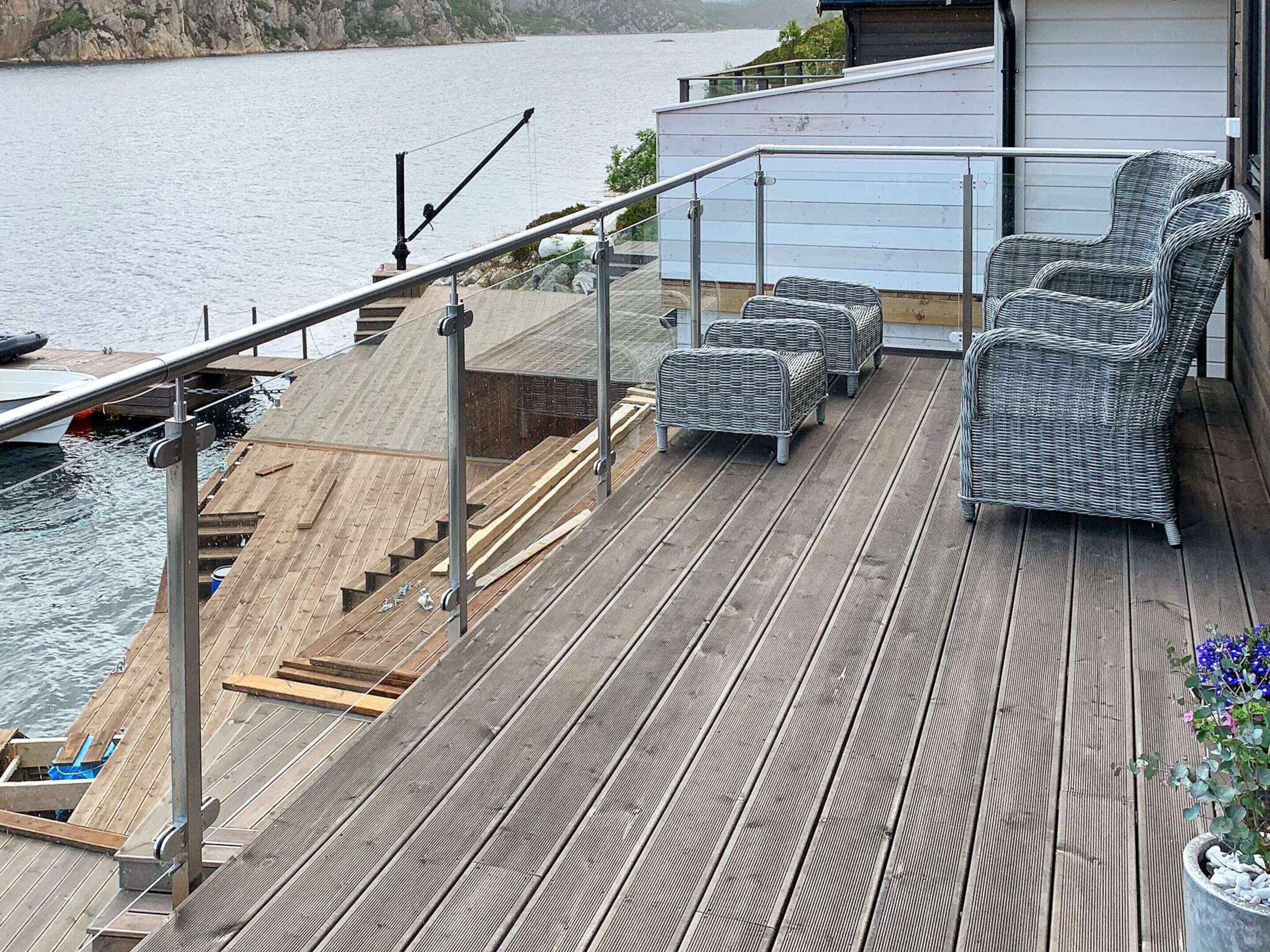 A wooden deck with outdoor furniture, a railing, and a view of the water.