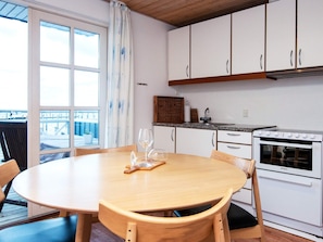 A kitchen with white cabinets, a white stove, and a dining table with chairs. - Holiday Home in GrenÃ¥ near Sea (Grenaa)