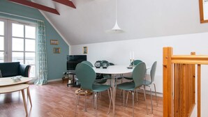 A dining area with a white table, green chairs, and a hanging light fixture. - Holiday Home in GrenÃ¥ near Sea (Grenaa)
