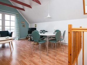 A dining area with a white table, green chairs, and a hanging light fixture. - Holiday Home in Grenå near Sea (Grenaa)