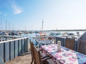 A wooden deck with a table and chairs, overlooking a marina with boats and a pier. - Holiday Home in GrenÃ¥ near Sea (Grenaa)