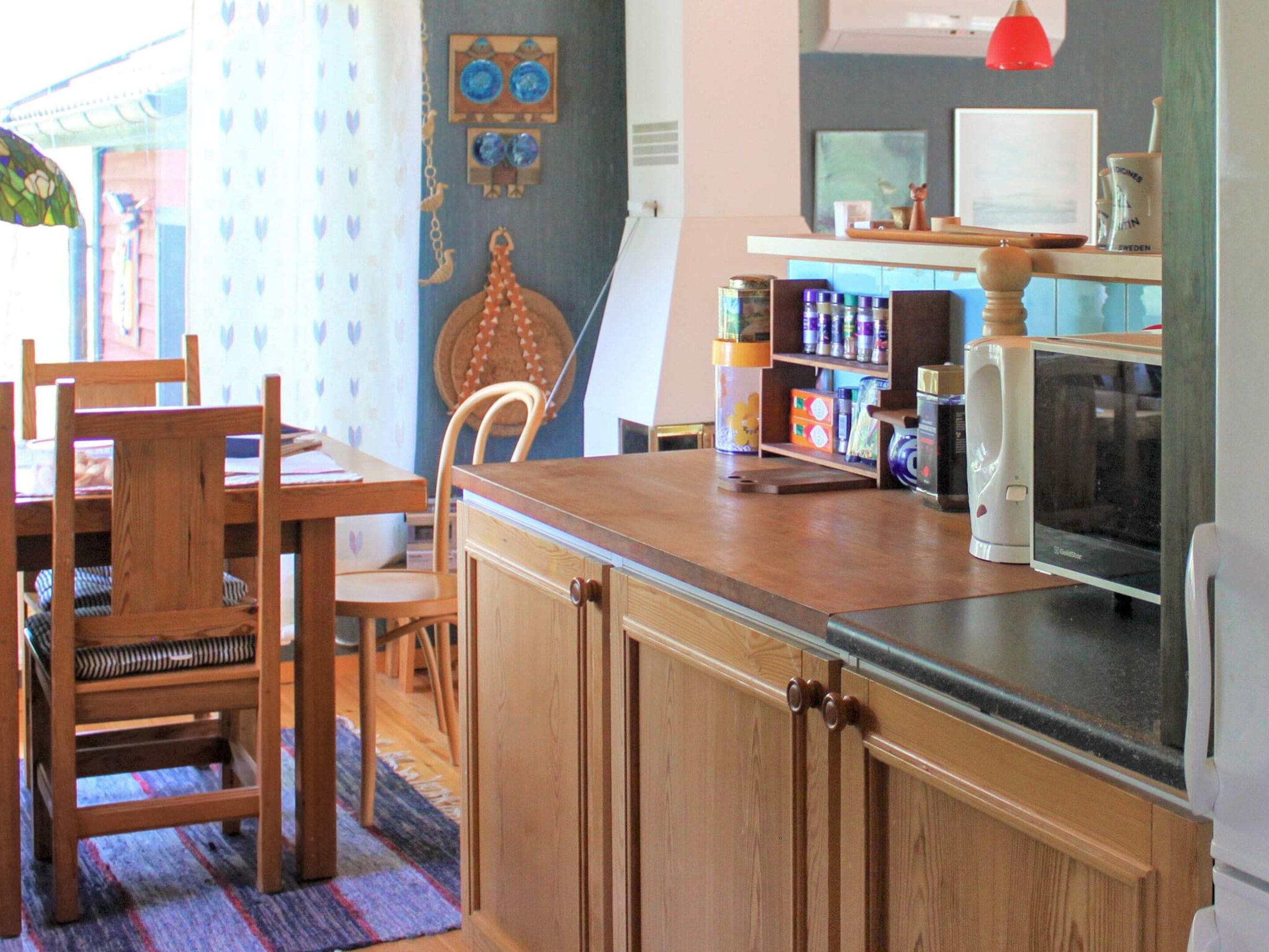 Una cocina compacta con armarios de madera, una mesa de comedor con sillas, un microondas y una cafetera.